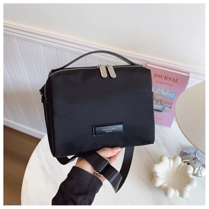 Détail d'un sac bandoulière en nylon noir avec double zip et large sangle réglable