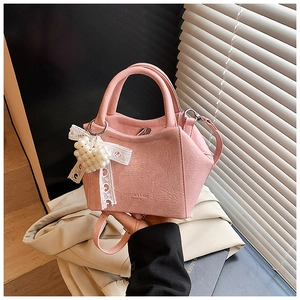 Dettaglio borsa a secchiello rosa con trama litchi e ciondolo con fiocco di perle