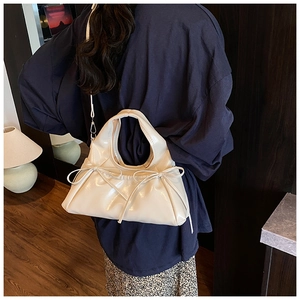 Detail of off-white glossy leather handbag featuring two stylish decorative bows