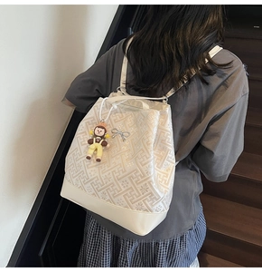 Detail of cream jacquard backpack with floral patterns, silver bow, and a cute charm