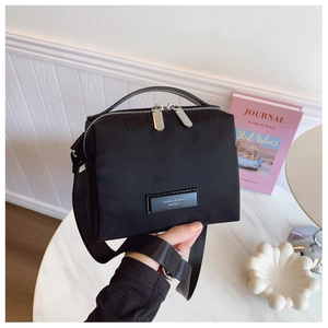Vue détaillée du sac bandoulière noir en nylon avec poignée sur une table en marbre