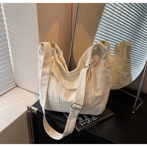 Detail of white canvas tote bag featuring distressed pocket edges and adjustable strap