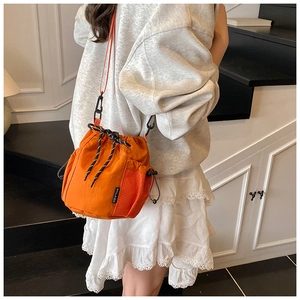 Bright orange nylon bucket bag with drawstring closure and side mesh pocket detail