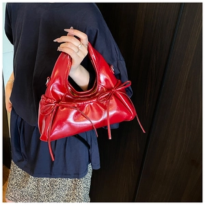 Detail of red glossy PU leather handbag with elegant bow decoration and ruffled design