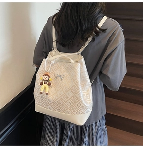 Detail of cream tote bag with floral relief texture and a cute cartoon pendant