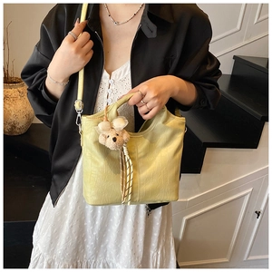 Detail of lime yellow bucket bag with crocodile pattern and plush bear charm