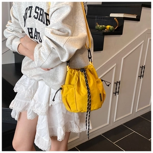 Detail of yellow nylon drawstring bucket bag showing side mesh pocket and cord accents