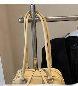 Détail du sac à main en cuir jaune pâle avec de longues bretelles et double fermeture éclair