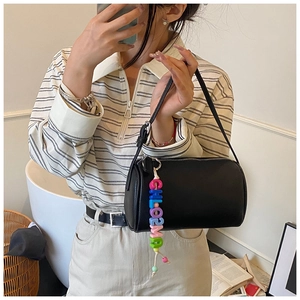 Detail of black lychee grain cylinder bag featuring colorful CHLOE letter bead charm