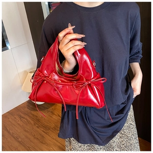 Detail of red glossy leather handbag with side bow knots and smooth zipper closure