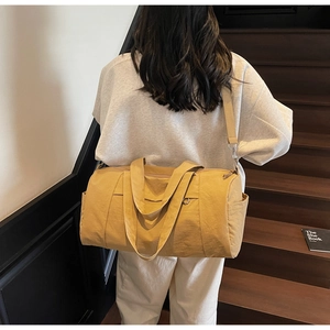 Close-up of bright yellow nylon travel bag with shoulder strap on a wooden staircase