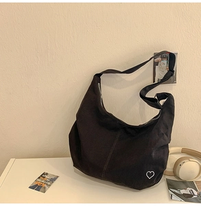 Close-up of black canvas crossbody bag with white heart embroidery and zipper closure