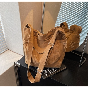 Detail view of caramel denim bag featuring vintage distressed frayed edges and metal buckle