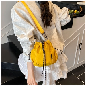 Detail of yellow nylon drawstring bucket bag featuring a side mesh pocket and adjustable strap