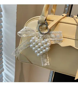 Détail du pendentif en perles en forme de cœur avec un nœud en dentelle blanche sur un sac
