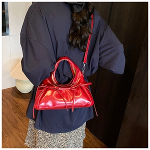 Detail of red glossy PU leather shoulder bag with chic bow accents and ruched cloud design