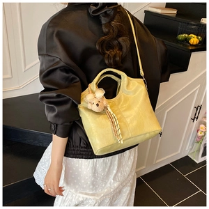 Detail view of light green bucket bag with crocodile texture and cute bear charm