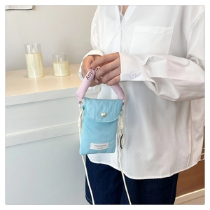 Light blue nylon crossbody bag with a white pearl accent and pink 'nice day' handle