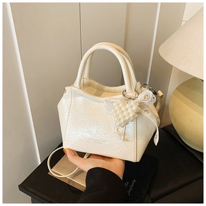 Dettaglio mini borsa a secchiello in pelle plissettata crema con cuore di perle e fiocco