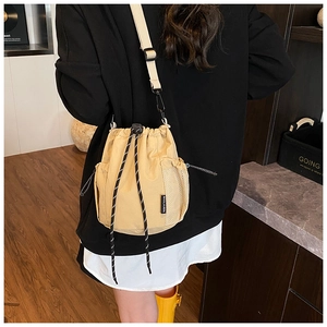 Detail of khaki canvas drawstring bucket bag with mesh side pocket and adjustable strap