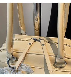 Détail des doubles fermetures éclair en métal et du pendentif en perles sur le sac jaune