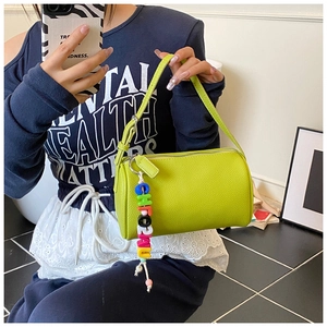 Detailed shot of lime green lychee pattern cylinder handbag with a colorful charm