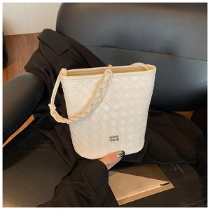Detail view of woven leather bucket bag featuring a braided handle and metal logo plaque