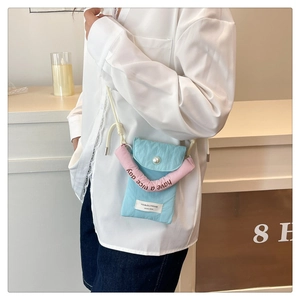 Detail of blue mini crossbody phone bag with pink handle and white pearl button closure
