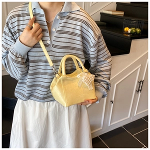 Dettaglio della mini borsa a secchiello giallo pallido con texture litchi e perle