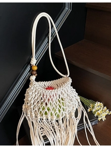 White macrame woven shoulder bag with long fringe and decorative wooden beads