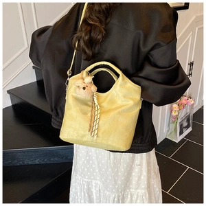 Detail of yellow crocodile embossed handbag with a plush bear charm on its handle