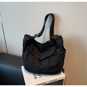 Detail of black canvas tote bag with front flap pocket and adjustable shoulder strap