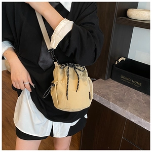 Detail view of khaki drawstring bucket bag with functional mesh side pocket and striped cord