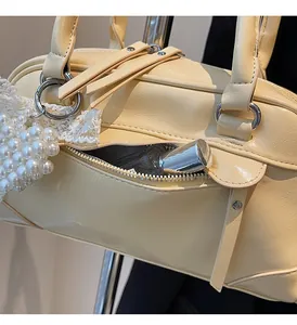 Détail du sac Boston jaune avec breloque en dentelle et poche zippée fonctionnelle