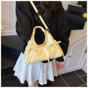 Detail of a yellow glossy bow handbag with a detachable strap for multiple wearing styles