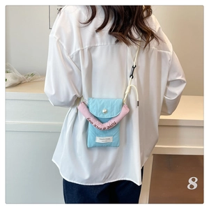 Model wearing a small blue and pink crossbody phone bag with brand patch detail