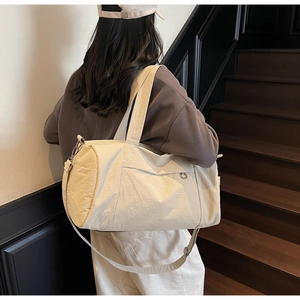 Cream large capacity travel tote bag with adjustable shoulder strap and side pocket detail