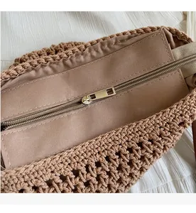 Detail of smooth gold zipper closure on large woven straw beach shoulder bag