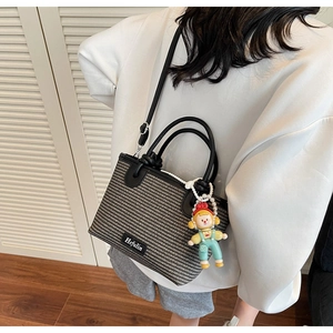 Close-up of woven bucket bag featuring cute doll charm and pearl chain detail