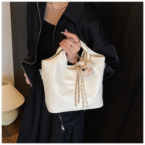 Detailed texture of white crocodile pattern tote bag with a cute plush bear pendant