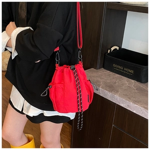 Detailed view of red drawstring bucket bag with woven cord and adjustable strap