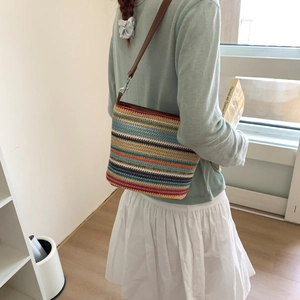Bohemian striped woven shoulder bag with brown leather strap shown on a model