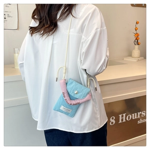 Detail of blue canvas crossbody bag with pearl buckle and pink decorative strap