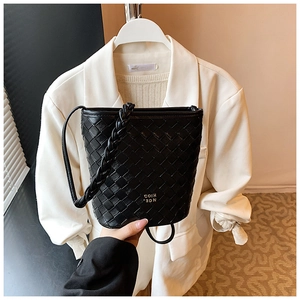 Detailed view of black woven leather bucket bag with top handle and embossed logo