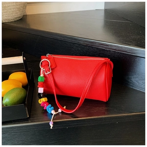 Close-up of red lychee pattern barrel bag with a colorful rainbow letter charm detail