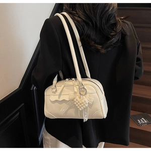Close-up of off-white faux leather Boston bag with lace and pearl heart charm accessory