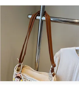 Detail of woven straw tote bag with brown leather straps and cute hat doll charm