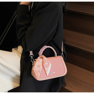 Detailed shot of pink leather handbag with heart-print scarf handle and silver hardware