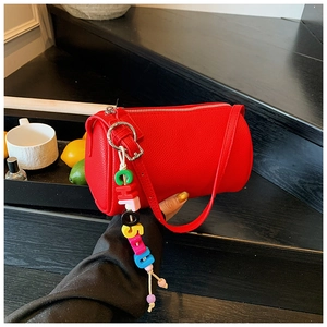 Close-up of red litchi grain cylinder bag with colorful letter bead charm detail