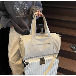 Detailed view of beige travel duffel bag on luggage handle showing nylon texture and strap